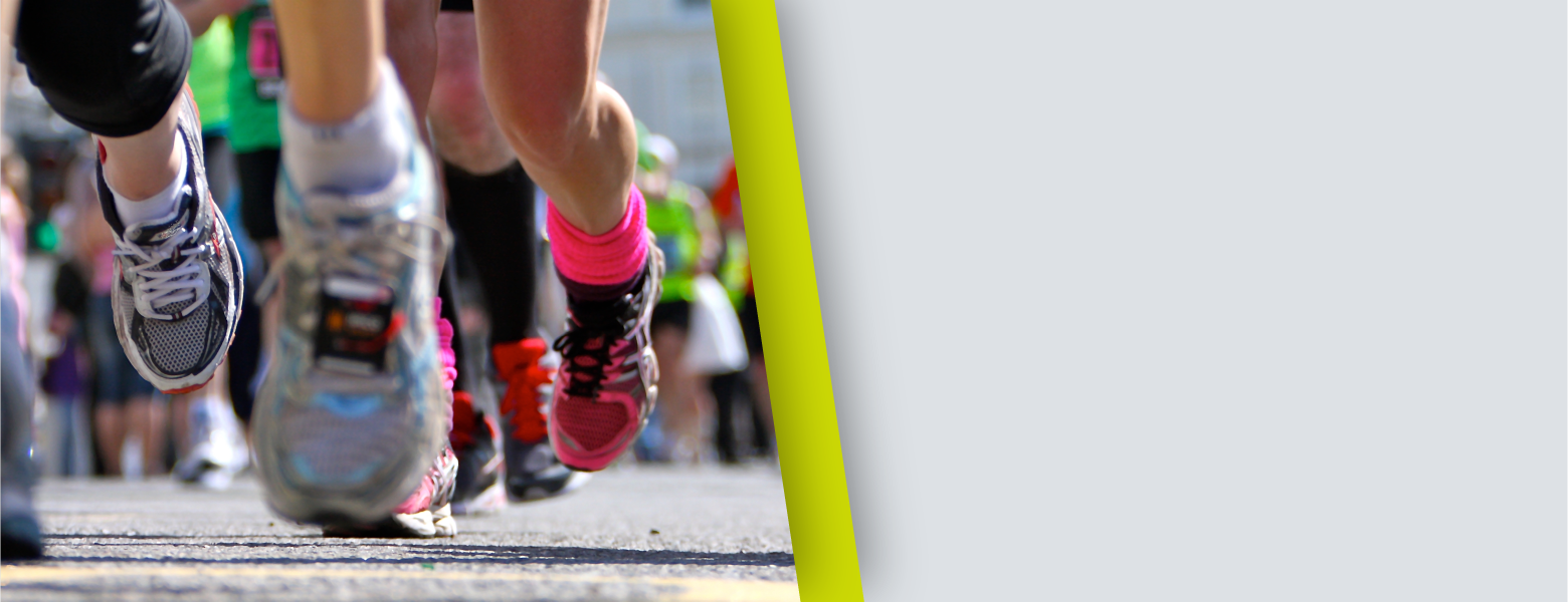 Close-up of runners' legs and colorful athletic shoes on a street during a race, blurred crowd in background, energetic